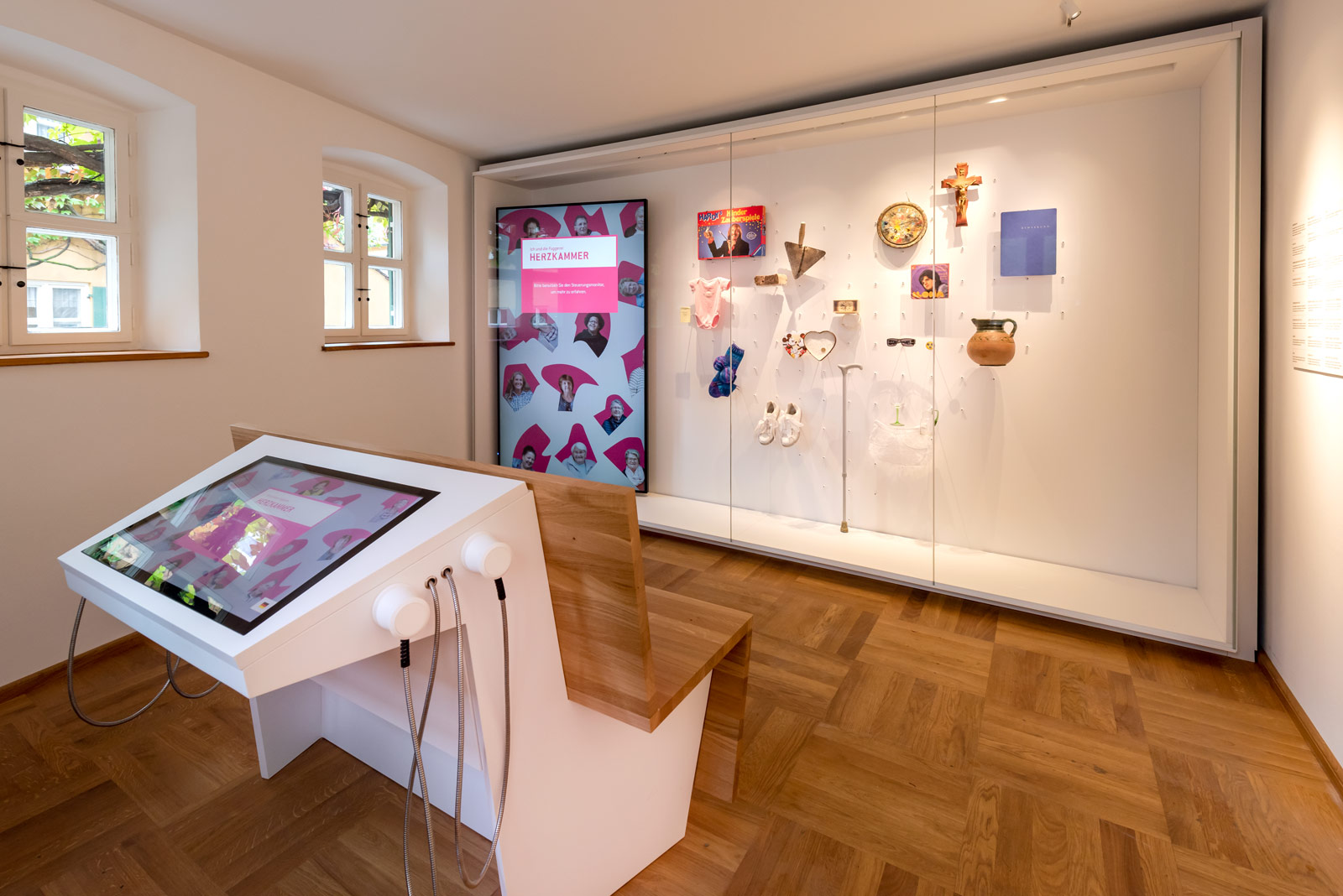 Das Referenzbild für Ausstellungsgestaltung aus der Dauerausstellung Museum der Bewohner zeigt eine Vitrine und eine Medienstation mit Touchscreen