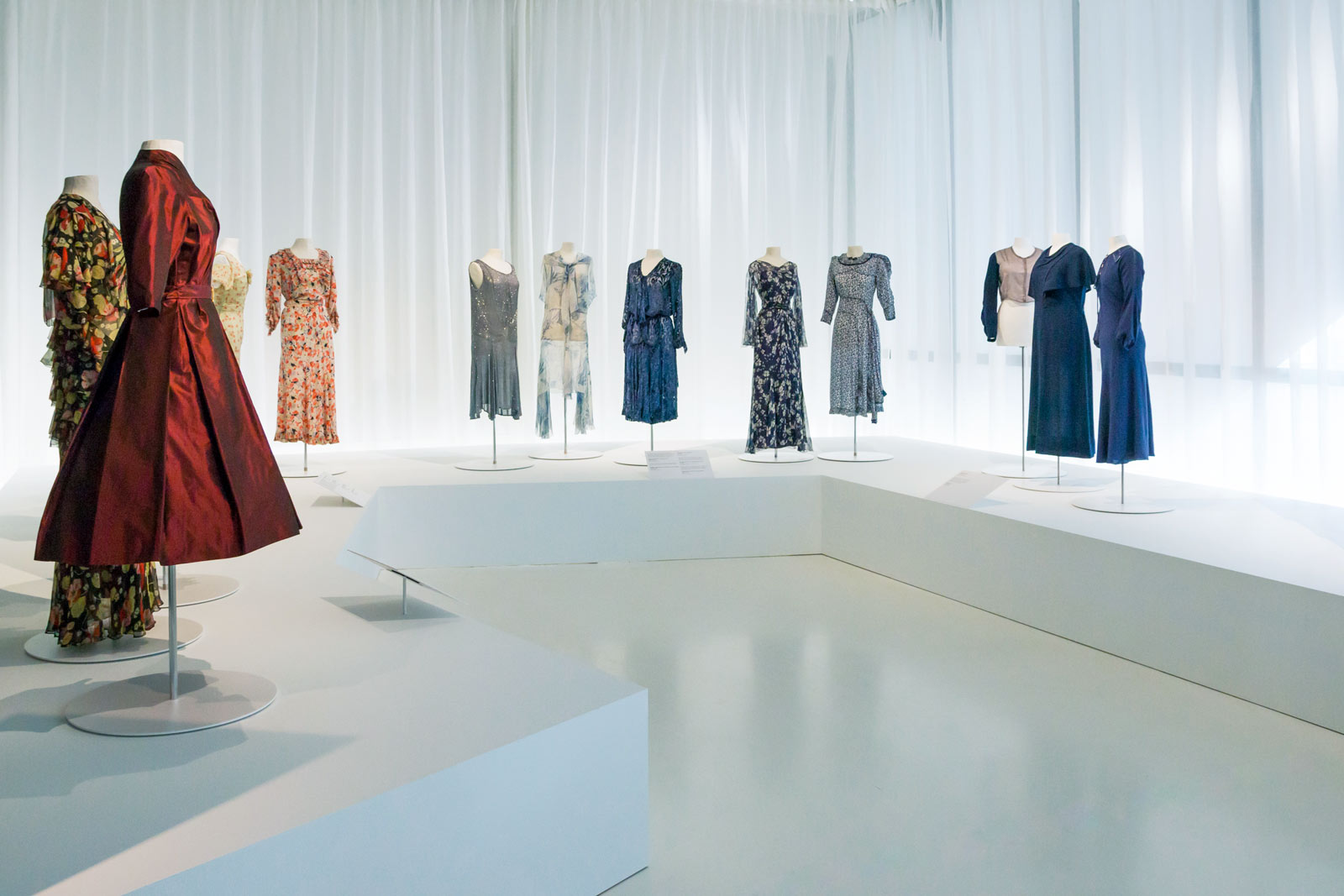 Das Referenzbild für Ausstellungsgestaltung aus der Sonderausstellung „Glanz und Grauen. Mode im Dritten Reich“ zeigt die Exponatpräsentation historischer Kleidungsstücke.