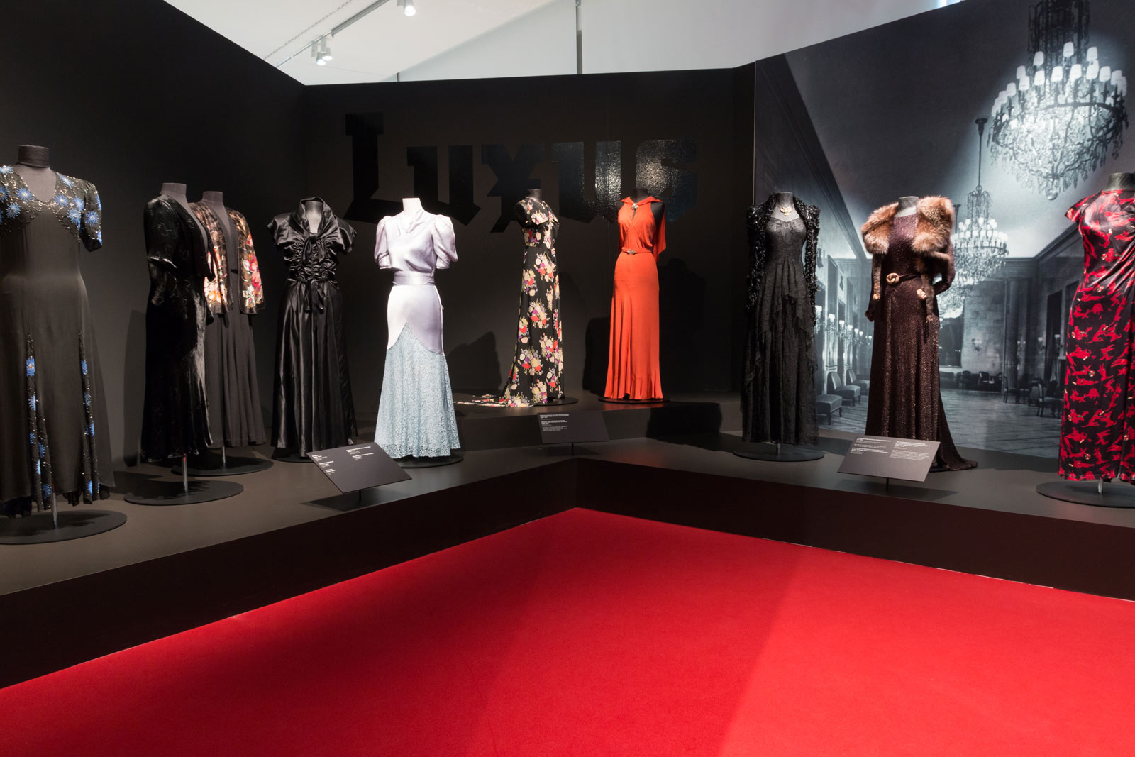 Das Referenzbild für Ausstellungsgestaltung aus der Sonderausstellung „Glanz und Grauen. Mode im Dritten Reich“ zeigt eine Exponatpräsentation historischer Kleidungsstücke.