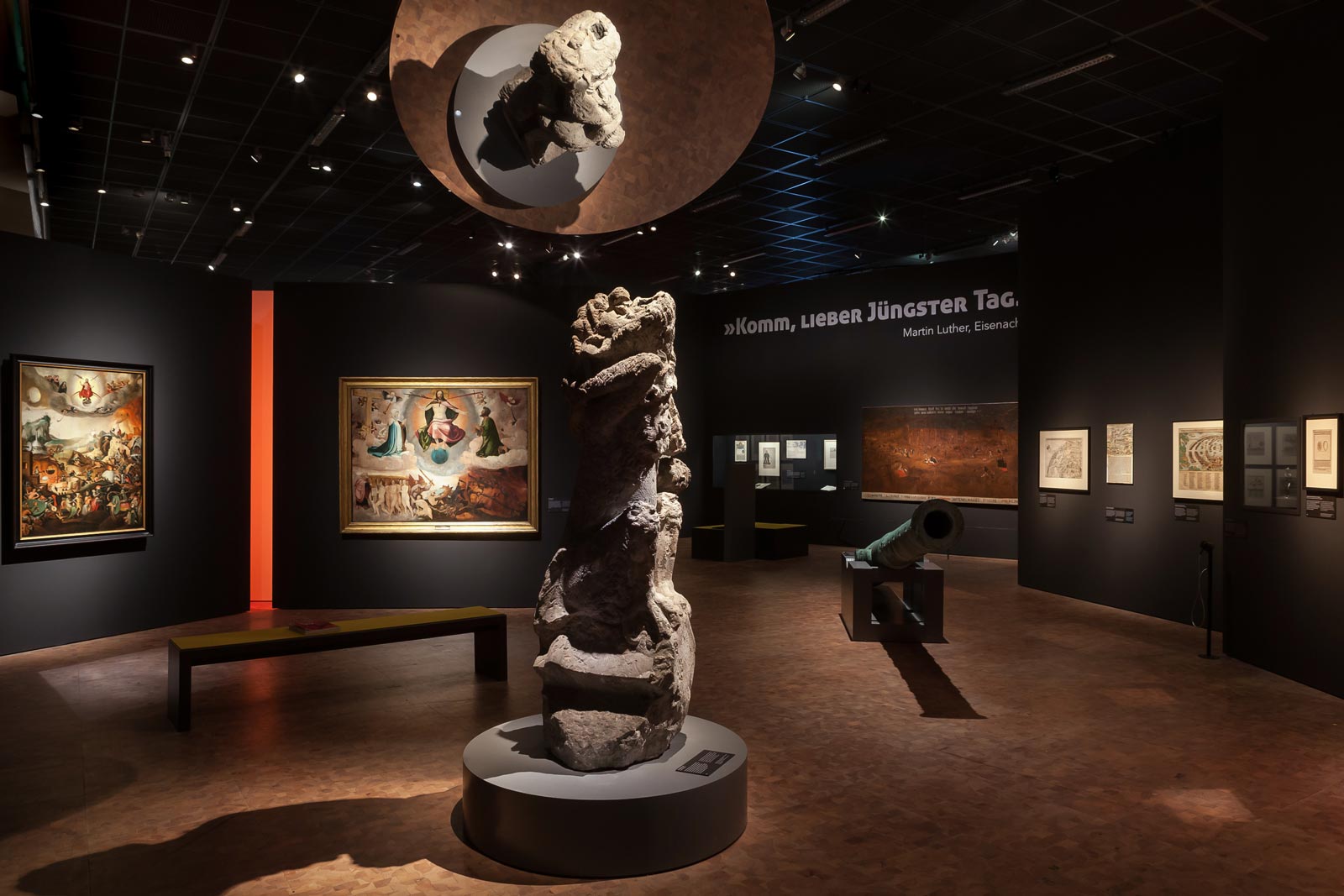 Das Referenzbild für Ausstellungsgestaltung aus der Sonderausstellung Luther, Kolumbus und die Folgen zeigt eine Szenografie mit Wandgrafik und Exponatbeleuchtung.