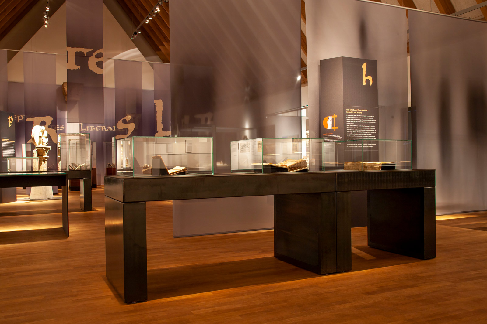 Das Referenzbild für Ausstellungsgestaltung aus der Sonderausstellung „Macht des Wortes“ zeigt eine Exponatpräsentation in Tischvitrinen.