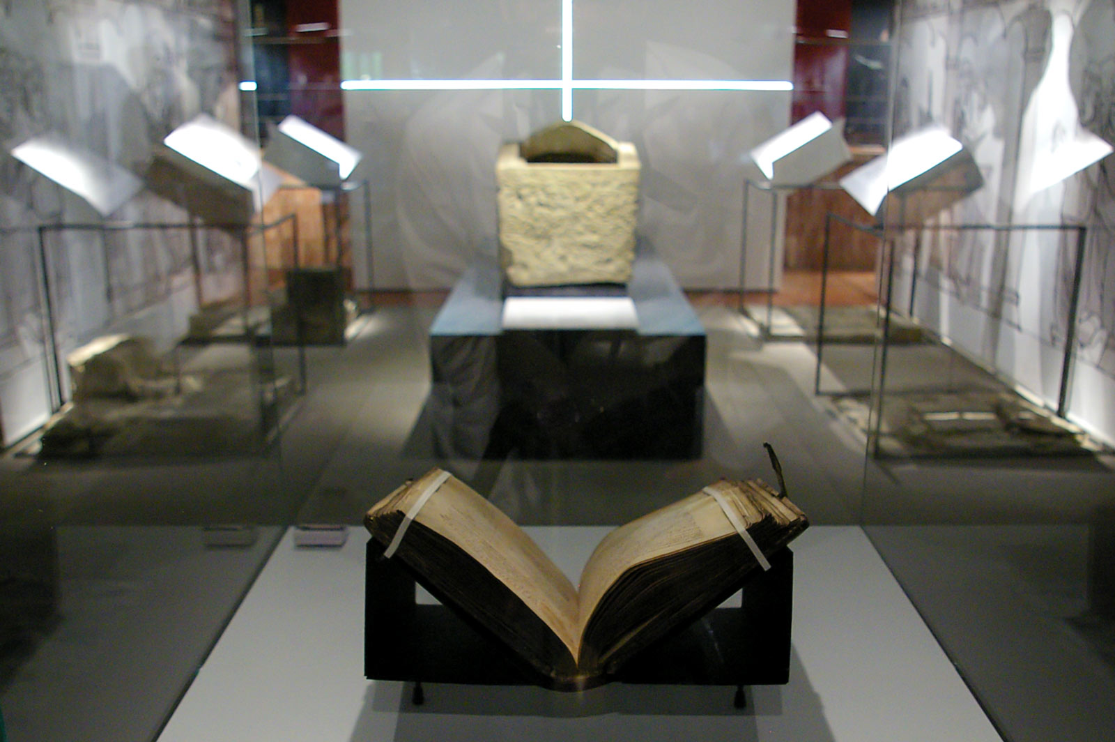 Das Referenzbild für Ausstellungsgestaltung aus der Sonderausstellung „Canossa 1077. Erschütterung der Welt“ zeigt eine Rauminszenierung mit Exponatpräsentation in einer Buchlege.